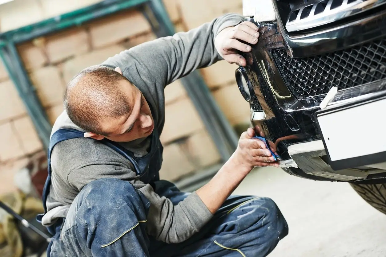 Technician repairing a vehicle front bumper
