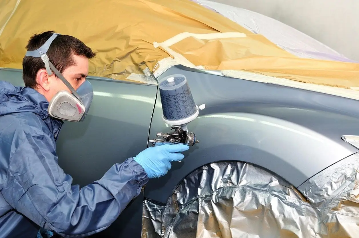Auto body painter refinishing a car in the paint booth at Collision Icon